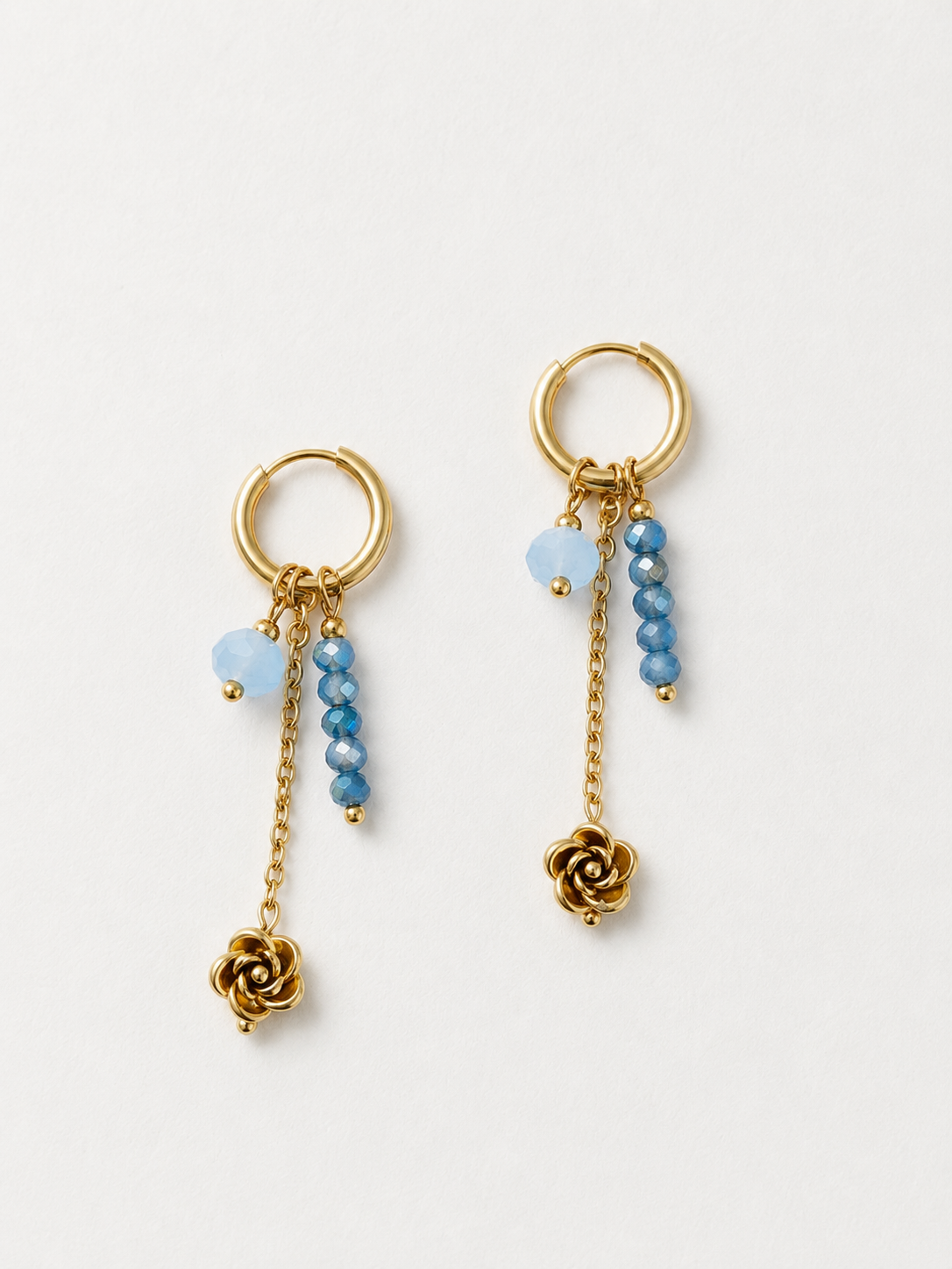 Handgemaakte gouden RVS oorbellen met lichtblauwe en donkerblauwe kralen en een gouden roosje, hangend aan een kleine gouden ring