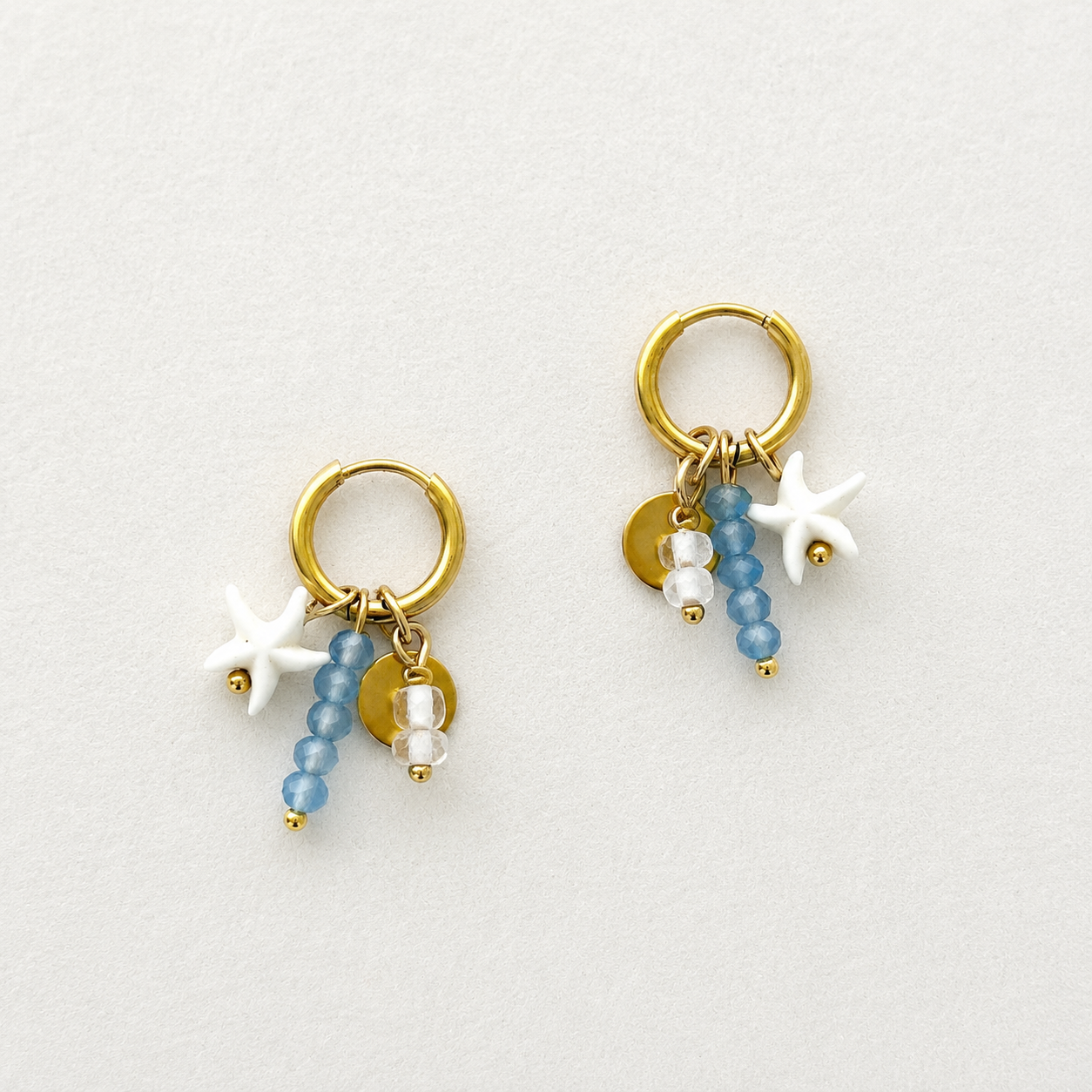 Handgemaakte gouden RVS oorbellen met witte zeester, blauwe kralen en gouden muntje aan kleine gouden hoepel