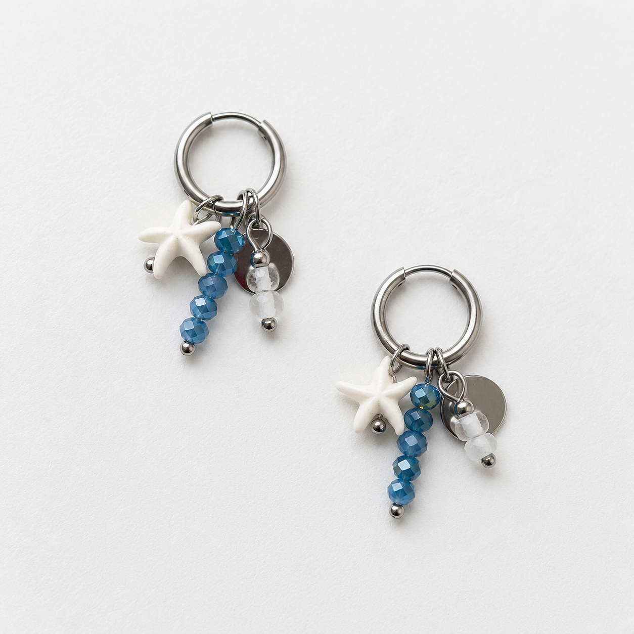 Handgemaakte zilveren RVS oorbellen met witte zeester, blauwe kralen en zilveren muntje aan kleine zilveren hoepel