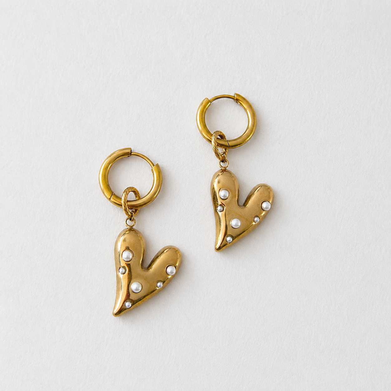 Handgemaakte statement oorbellen met gouden hart bezet met witte parels aan 12mm RVS ring