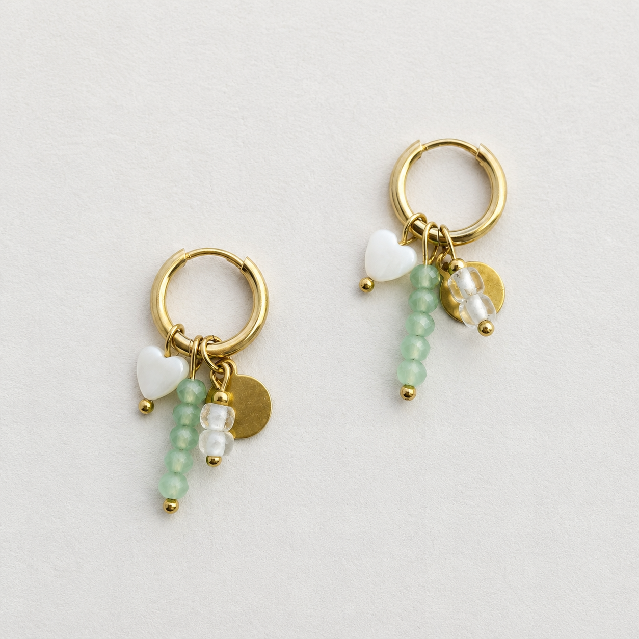 Handgemaakte gouden RVS oorbellen met mintgroene kristalkralen, wit porseleinen hartje en gouden muntje aan kleine gouden oorbel ring