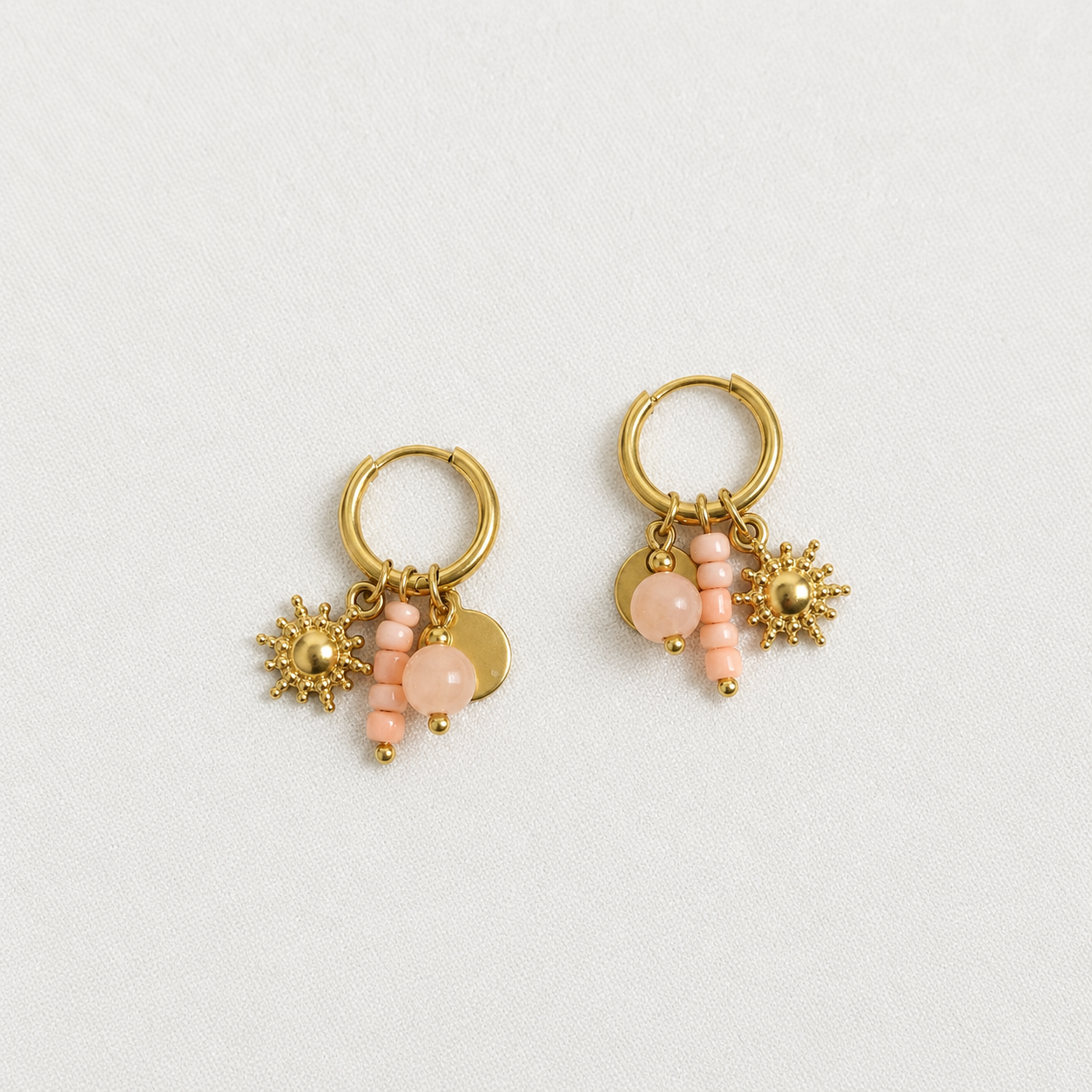 Handgemaakte gouden RVS oorbellen met perzikroze kralen, gouden zon-bedel en hartje muntje aan kleine gouden oorbelring
